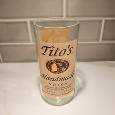 a glass filled with liquid sitting on top of a counter next to a tile wall