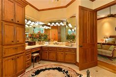 a large bathroom with wooden cabinets and marble counter tops, along with a rug on the floor