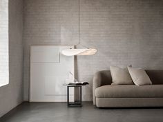 a living room with a couch, table and lamp hanging from the ceiling in front of a brick wall