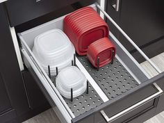 two red and one white containers are sitting in the bottom drawer of a kitchen cabinet