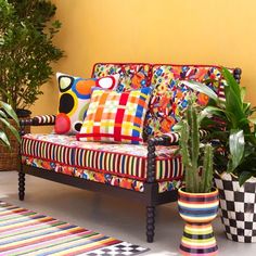 a brightly colored couch sitting on top of a rug next to potted plants