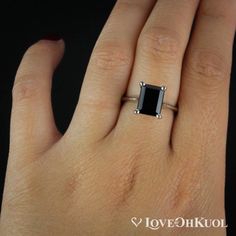 a woman's hand with a black diamond ring on it