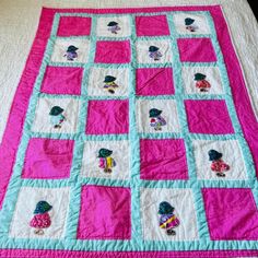 a pink and blue quilt on top of a bed