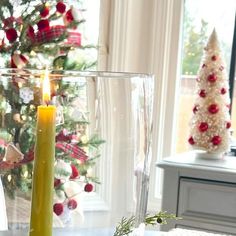 a lit candle sitting on top of a table next to a christmas tree