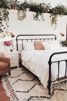 a bedroom with plants hanging on the wall and a bed in the middle, next to a chair