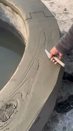 a person is using a knife to paint the side of a large piece of cement