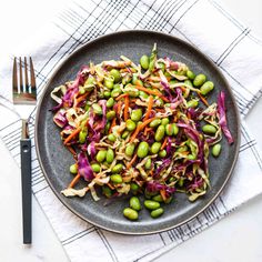 a plate filled with vegetables and sprouts next to a fork