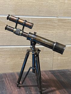 an old telescope on a tripod in front of a wooden wall