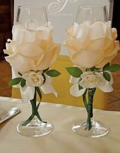 two wine glasses sitting on top of a table with white flowers in them and one is empty