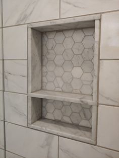 an empty shelf in the middle of a tiled wall