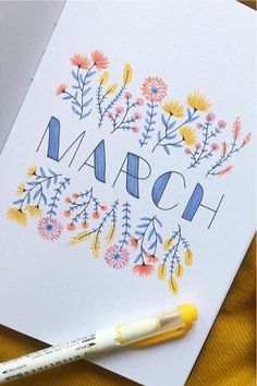 a card with the word march written on it next to a marker and some flowers