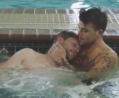 two men are in the swimming pool and one is holding his face to each other