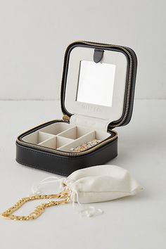 an open black jewelry box sitting on top of a white table next to a gold chain