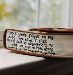 an open book with writing on it sitting on a window sill next to a window