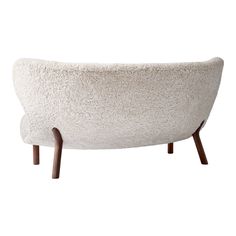 a white couch with wooden legs and a sheepskin pattern on the back, sitting in front of a white background