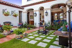 an outdoor patio with potted plants and chairs on the grass in front of it