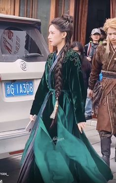 two women dressed in medieval costumes walking down the street with one woman wearing a green dress