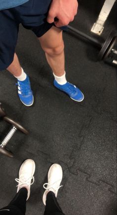 a man with blue shoes standing next to a barbell