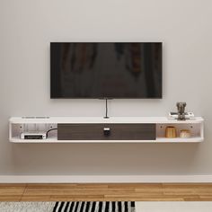 a flat screen tv mounted to the side of a white wall next to a wooden floor