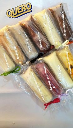 several different types of desserts wrapped in plastic on a white tablecloth with the words quero printed on it