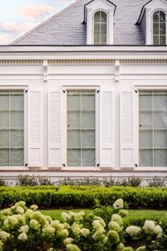 a house with white shutters and green bushes