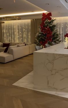 a living room filled with white couches and a christmas tree in the middle of it