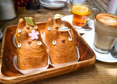 there are some food shaped like animals in a tray on the table next to a cup of coffee