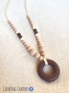 a wooden beaded necklace with a brown and white ring hanging from it's end