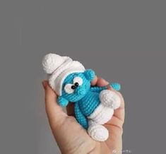 a hand holding a small crocheted blue and white stuffed animal