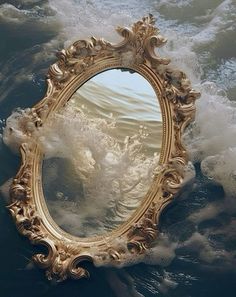 an ornate gold framed mirror floating in the middle of some water with foamy waves around it