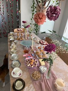 the table is set up with desserts and teacups for guests to enjoy