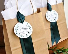 two brown paper bags with green ribbons and tags on them, sitting on a table