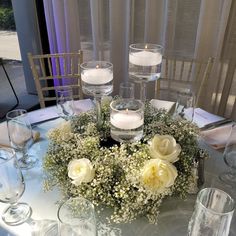 a centerpiece with flowers and candles on a table