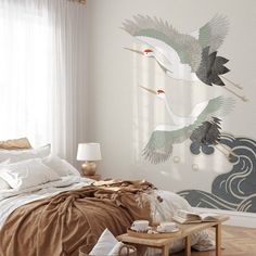 two birds flying over a bed in a room with white walls and wood flooring