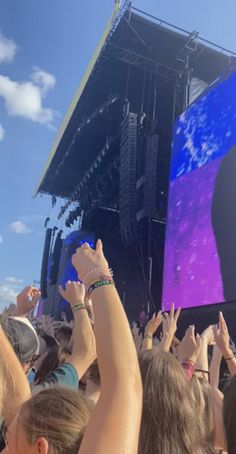 a large group of people at a concert with their hands in the air