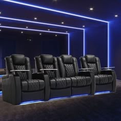 a row of black leather chairs in front of a projector screen with blue lights