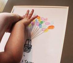 a child's hand holding onto a card with balloons attached to the back of it