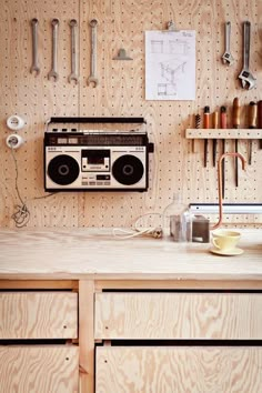 an old radio sits on top of a wooden cabinet in a workshop with tools hanging from the wall