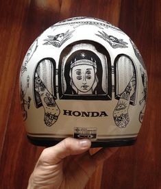 a person holding up a motorcycle helmet with an image on it