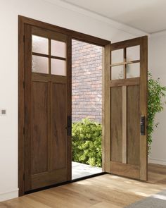 an open wooden door in front of a brick wall and green plant on the floor