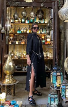 a woman standing in front of a store filled with lanterns