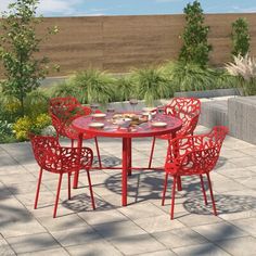 a red table and four chairs sitting on top of a stone floored patio area