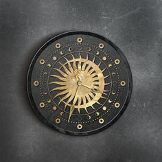 a black and gold clock on a gray surface with holes in the middle to indicate it's time