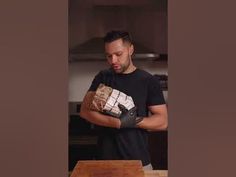 a man in black shirt holding a box on top of a wooden table