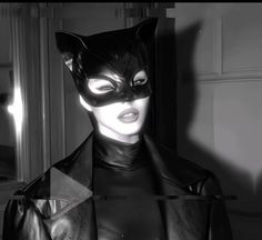 a woman dressed up as catwoman in a black and white photo with the light shining through her eyes