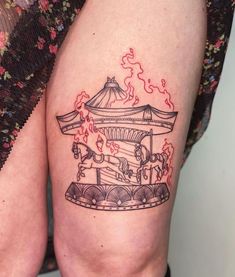 a woman's thigh with a carousel tattoo on her left leg and an orange fire coming out of it