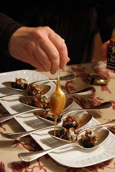 a person is dipping sauce on food in small bowls with spoons to eat it