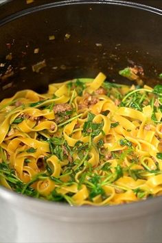 a pot filled with pasta and greens on top of a stove