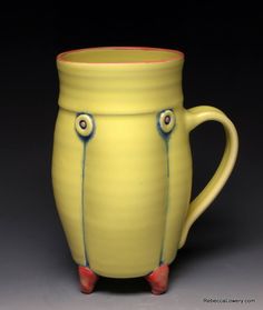 a yellow mug with red feet and handles