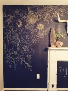 the wall is painted with flowers on it and has a chalkboard in front of it